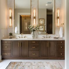 a bathroom with two sinks, mirrors and lights on the wall above it's double vanity