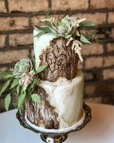 a wedding cake decorated with succulents and greenery