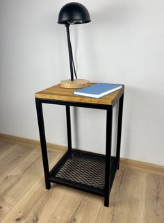 a wooden table with a lamp on top and a book sitting on the shelf next to it