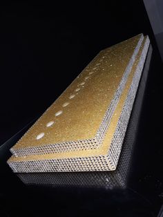 a piece of metal that has been coated with gold flecks and is sitting on a black surface