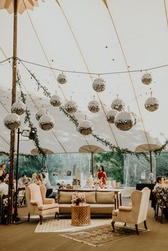 a large tent with people sitting at tables and hanging decorations on the ceiling above it