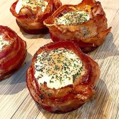 four bacon wrapped in cheese and herbs on a wooden cutting board with other food items