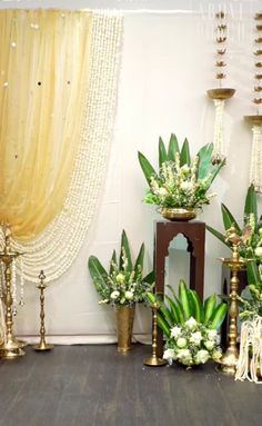 an arrangement of flowers and candles on display in front of a curtained window with gold drapes