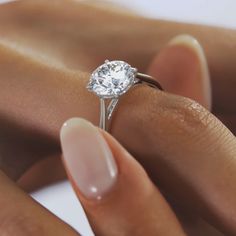 a close up of a person's hand holding a ring with a diamond on it