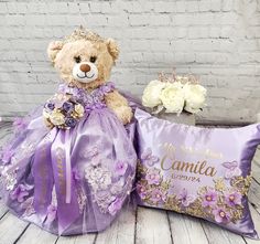 a teddy bear sitting next to a pillow with a tiara and flowers on it