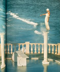 an open book shows a woman standing on top of pillars in the water, with her arms outstretched