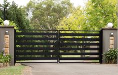 an iron gate with two gates on each side and trees in the backgroud