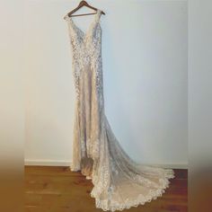 a wedding dress hanging on a hanger in a room with wood floors and white walls