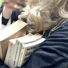 a woman is holding several books in her hands