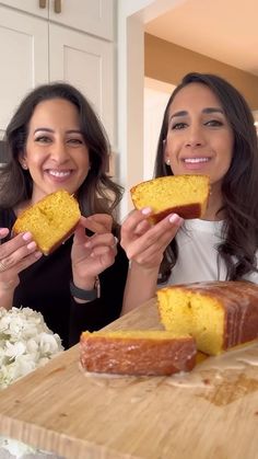 two women holding slices of cake on a cutting board