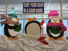 three penguins with hats and scarves on their heads are standing in front of a sign that says, buy your head in a good book