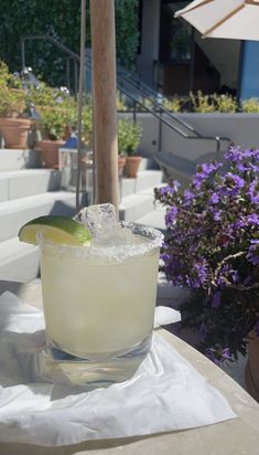 a margarita sitting on top of a table next to purple flowers