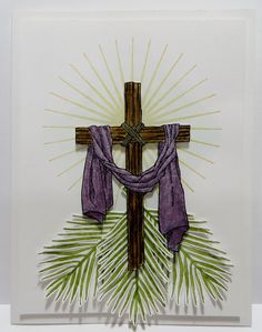 a cross with purple cloth hanging from it's center surrounded by green palm leaves