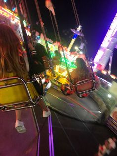 two people riding on a carnival ride at night