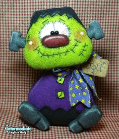 a green and purple stuffed animal sitting on top of a red checkered couch next to a tag