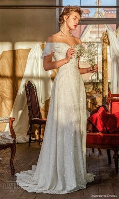 a woman standing in front of a mirror wearing a white dress and holding a bouquet