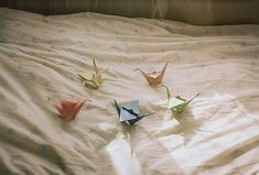 three origami birds on a bed with white sheets