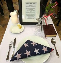 a white table topped with a plate and silverware next to a framed poster on the wall