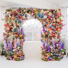 an arch made out of flowers in front of a window