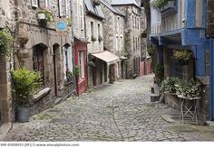 an old cobblestone street with stone buildings and potted plants on either side