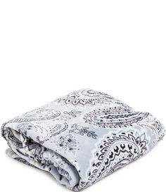 the blue and white paisley print blanket is folded up on top of a white surface