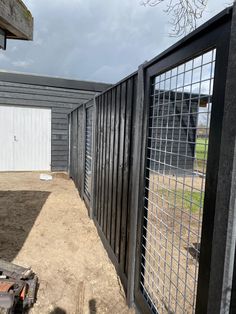 a fenced off area with a garage and gate in the background, on a cloudy day