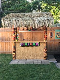 a tiki bar in the backyard with grass covering it and decorations on the outside