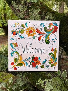 a welcome sign hanging from the side of a tree