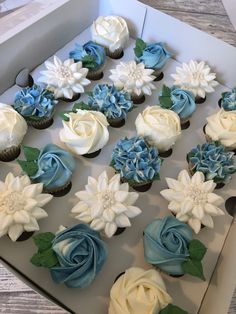 cupcakes decorated with blue and white flowers in a box