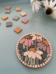 a plate that has some flowers in it on a table next to white daisies