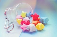 colorful origami stars are placed in a glass container on a blue and pink background