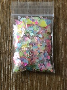 a bag filled with lots of colorful confetti on top of a wooden floor