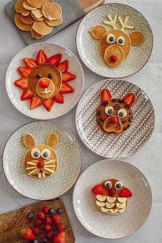 four plates with animal faces made out of pancakes and strawberries on the plate next to each other