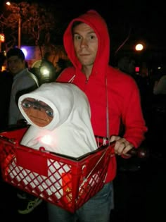 a man in a red hoodie is holding a basket with a stuffed animal inside