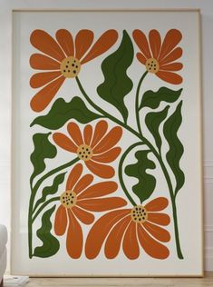 an orange and green floral print hangs on the wall