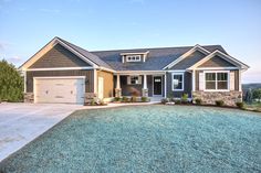 a house that is in the middle of a field with grass and bushes around it