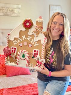 a woman is holding up a gingerbread house