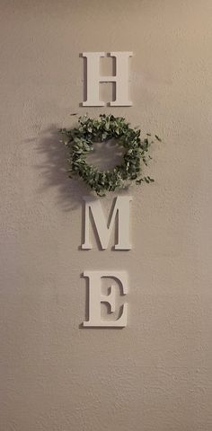 the word home is made out of metal letters and a wreath on top of it