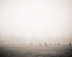 a group of people standing on top of a grass covered field