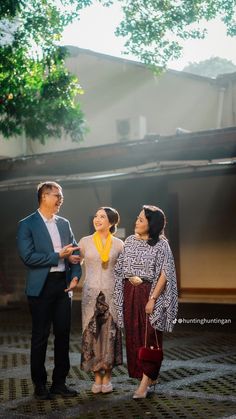 three people standing next to each other in front of a building