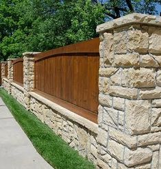 a wooden fence next to a stone wall