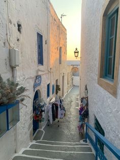 an alley way with clothes hanging on the wall and blue shutters in front of it