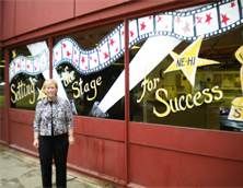 a woman standing in front of a business with signs on the windows that say for success