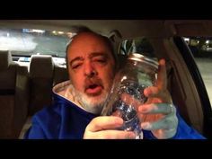 an older man holding a glass jar in his hand while sitting in the back seat of a car