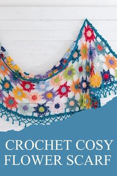 the crochet cosy flower scarf is hanging up against a white wall with text overlay that reads, crochet cosy flower scarf