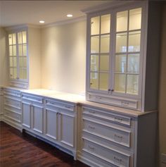 an empty kitchen with white cabinets and wood flooring in the middle of the room