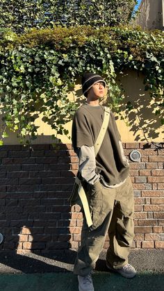 a man standing in front of a brick wall with ivy growing on it's side