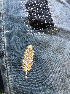 a pair of jeans that have been stitched together with some gold thread on them