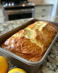 a loaf of bread sitting on top of a counter next to lemons and an orange