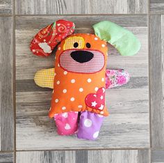 an orange stuffed animal with polka dots on it's face and legs sitting on a wooden floor